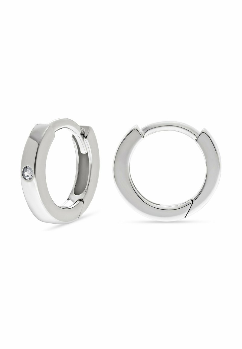 Orecchini a cerchio in argento con finitura liscia, uno dei quali presenta una piccola pietra preziosa tonda e trasparente, su uno sfondo bianco.