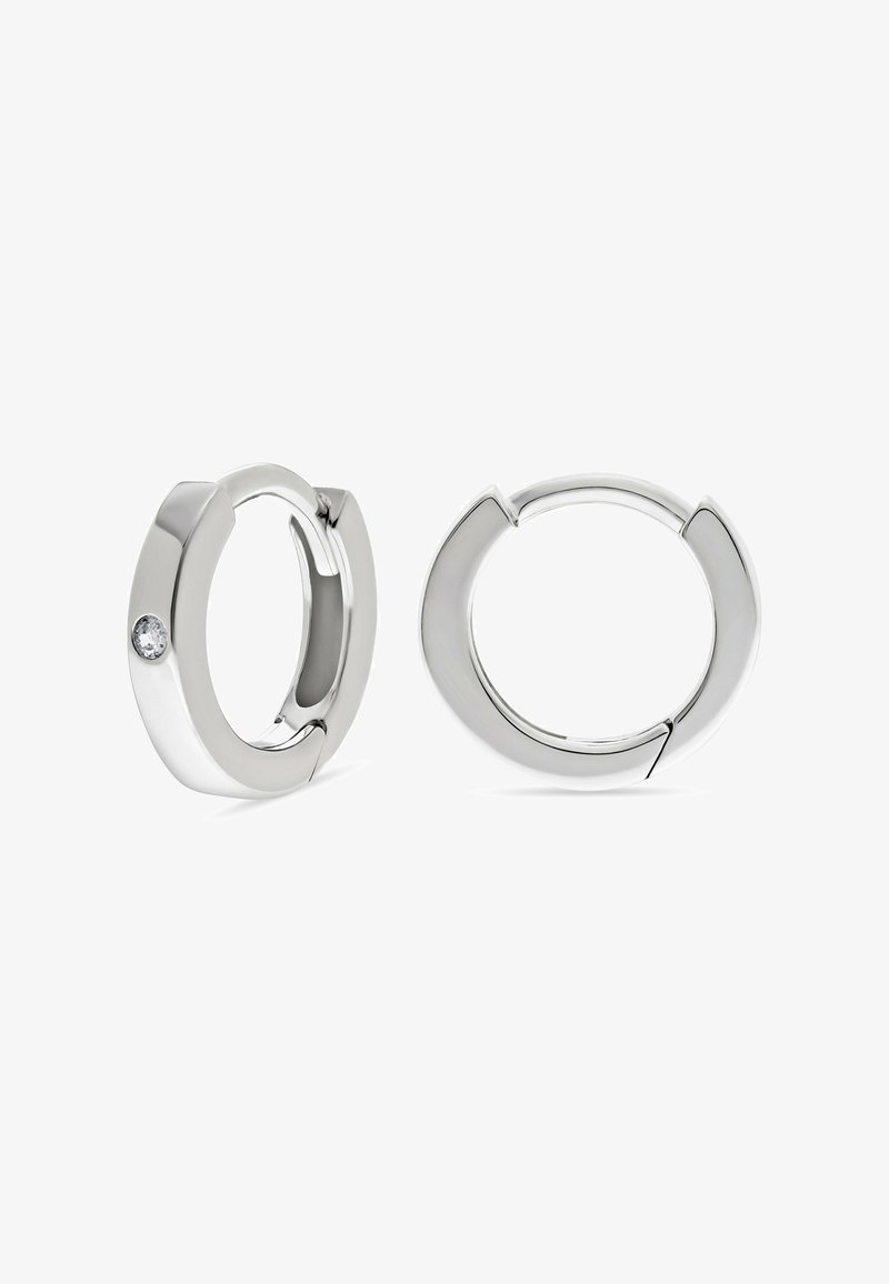 Orecchini a cerchio in argento con finitura liscia, uno dei quali presenta una piccola pietra preziosa tonda e trasparente, su uno sfondo bianco.