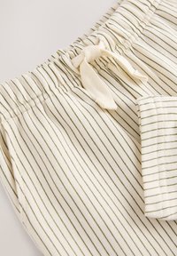 Bombažne kratke hlače z elastičnim pasom, z zelenimi tankimi črtami na krem ozadju in majhnim stranskim žepom.