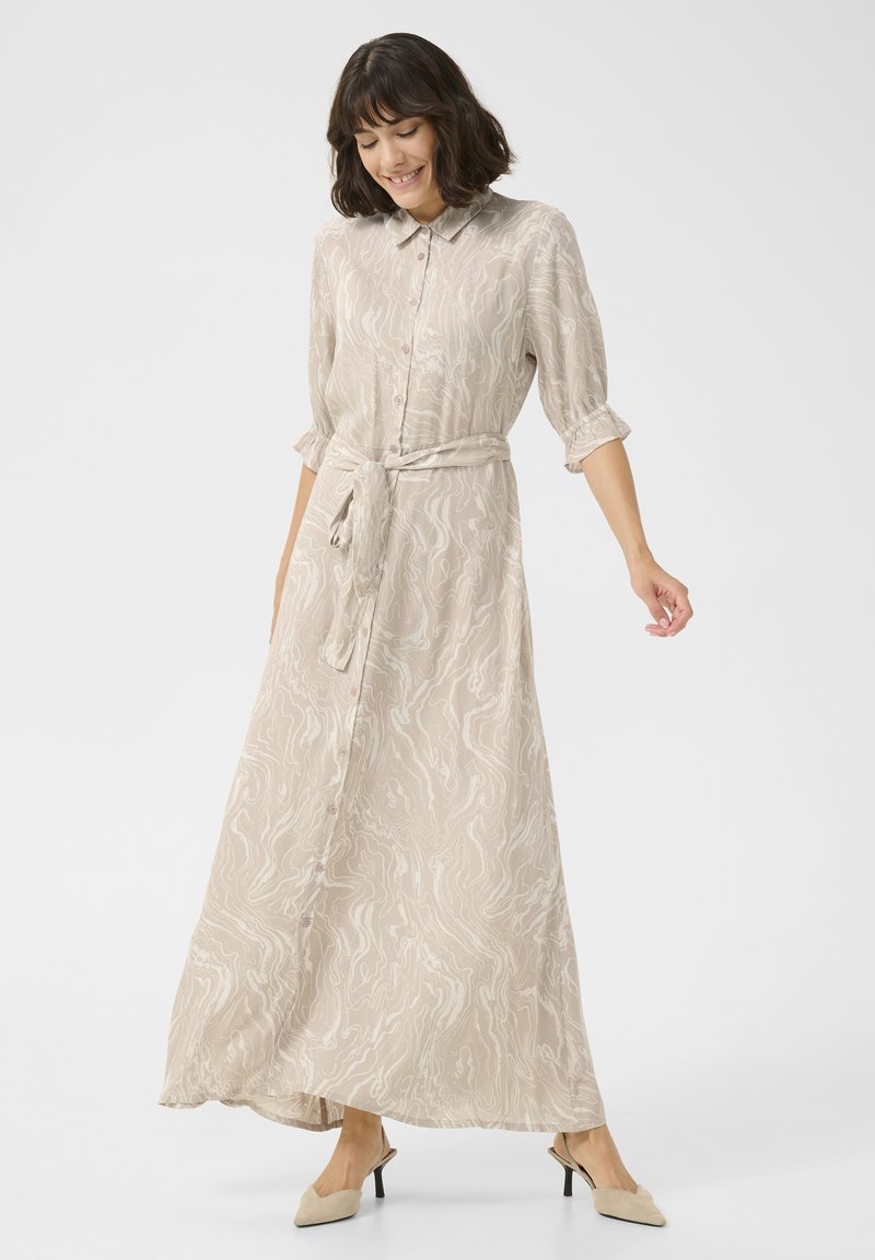 Robe longue beige avec un motif en vagues, col classique, ouverture à boutons et taille ajustable à nouer. Tissu léger avec des manches retroussées.