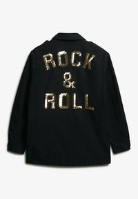 Chaqueta negra con el texto en lentejuelas doradas "ROCK & ROLL" en la parte de atrás, con un diseño de cuello y puños abotonados. Textura de tela suave.