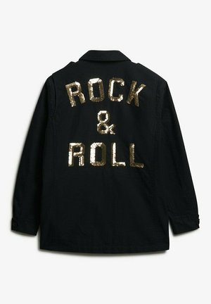 Chaqueta negra con el texto en lentejuelas doradas "ROCK & ROLL" en la parte de atrás, con un diseño de cuello y puños abotonados. Textura de tela suave.