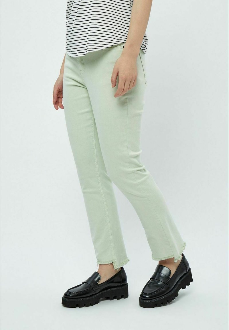 Bledo zelene slim-fit kavbojke z razfrkanim robom, v kombinaciji s črnimi robustnimi loaferji, nosijo jih z črtasto majico. Mehak denim material.
