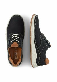 Schwarze Lederschuhe mit strukturiertem Finish, weißen Schnürsenkeln, kontrastierenden Nähten und beiger Gummisohle. Enthält einen braunen Akzent an der Ferse.