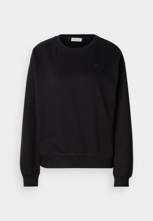 Melnā sporta krekla, kas izgatavots no mīksta materiāla, iezīme ir apaļa kakla izgriezuma forma, ribota aproce un neliels CK logo uz krūtīm. Vienkāršs, minimālistisks dizains.