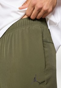 Πράσινο-ελ αιοχρώμιο αθλητικό σορτς με ελαστική μέση, πλαϊνή τσέπη και μαύρο λογότυπο Jordan μπροστά. Λείο, ελαφρύ ύφασμα.