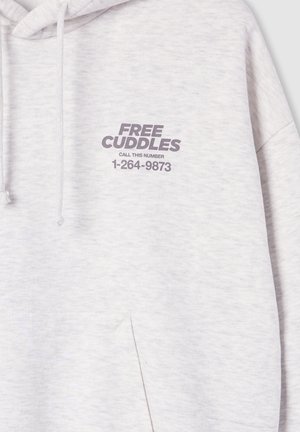 Jasnoszara bluza z kapturem z napisem "DARMOWE PRZYTULENIA ZADZWOŃ POD TEN NUMER 1-264-9873" wydrukowanym na lewej klatce piersiowej nad kieszenią.
