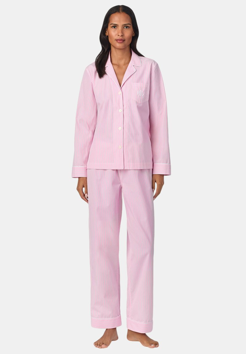 Un pyjama rayé rose et blanc, fabriqué en tissu doux, comprenant une chemise à boutons avec une poche et un pantalon long à bas de jambes resserrés.