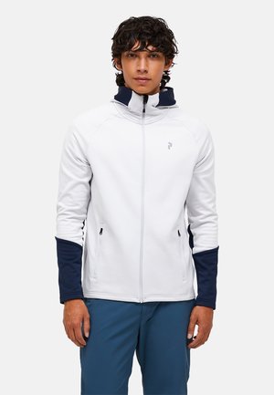 Hvid zip-jakke med marineblå accenter på ærmerne. Glat stof, høj krave og to sidelommer. Enkel logo på brystet.