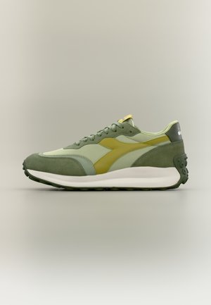 Zielony sneaker z mieszanką zamszu i siateczki, żółtym akcentem, zaokrąglonym kształtem oraz teksturowaną gumową podeszwą.