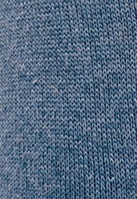 Tissu tricoté dans une teinte bleu clair avec un motif homogène, présentant une texture lisse et de fines coutures sur toute la surface.