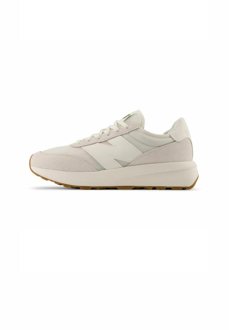 Sneaker in suede e mesh di un beige chiaro con logo bianco e suola in gomma. Presenta lacci piatti e una silhouette liscia e arrotondata.