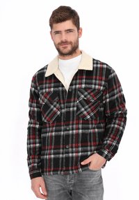 Chaqueta de cuadros hecha de tela de franela, con patrones en negro, rojo y gris, cuello de sherpa color crema y dos bolsillos en el pecho con solapas.