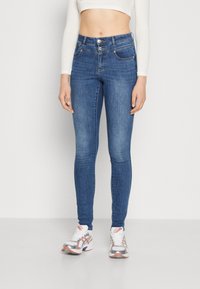 Közepes kék farmer skinny farmernadrág, magas derekú, két gombos záródással, elülső zsebekkel és enyhe fakulással a combok mentén.