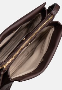 Borsa in pelle marrone con apertura zip, dotata di una fodera interna beige e diversi scomparti. Finiture in metallo dorato e zip.