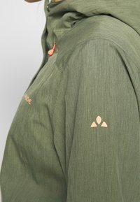 Green lightweight jacket with a textured finish, drawstring hood, and contrasting orange accents. Features a logo on the left shoulder.