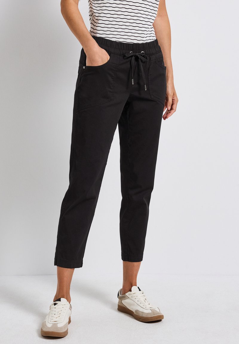 Schwarze Hose mit elastischem Bund und verstellbarem Kordelzug. Verfügt über seitliche Taschen und ein schmal zulaufendes Bein Design. Material aus Baumwollmischung.