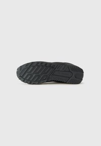 Black athletic shoe sole featuring a textured rubber surface with varying patterns for grip, and a molded design for durability.