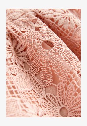 Różowa haftowana tkanina z skomplikowanymi wzorami kwiatowymi i geometrycznymi, o różnych fakturach i szczegółach w otwartym splocie.