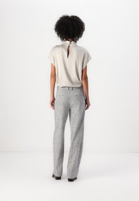 Un haut gris clair avec un détail en trou de serrure au dos, associé à un pantalon large à motifs gris et blanc. Tissu doux, design simple et coupe décontractée.