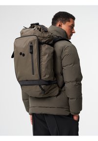Olivgrüner Rucksack mit strukturiertem Design, zwei schwarzen Punkten, verstellbaren Trägern und mehreren mit Reißverschluss versehenen Fächern.