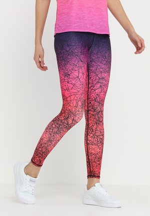 Leggings avec un dégradé du rose au violet et un motif abstrait de lignes noires, portés avec des baskets blanches et un haut rose.