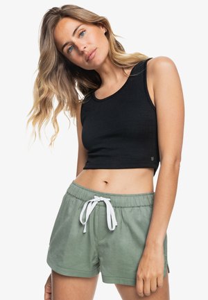 Black cropped tank top with a textured fabric, paired with green cotton shorts featuring a drawstring and side slits.