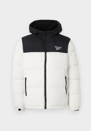 Podloga jakna v črni in beli barvi, z zadrgo, kapuco in dvema stranskima žepoma. Reebok logo na prsih. Teksturiran material.