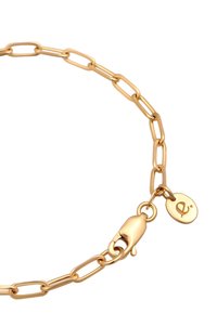 Gold-tone chain bracelet featuring elongated links, a lobster clasp, and a small circular charm with a logo. Smooth texture and shiny finish.