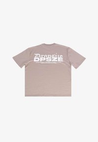 Beige Baumwoll-T-Shirt, kurze Ärmel, Rundhalsausschnitt. Rückseite mit großem weißen Grafiktext und Markenakzenten. Glatte Textur, lässiges Design.