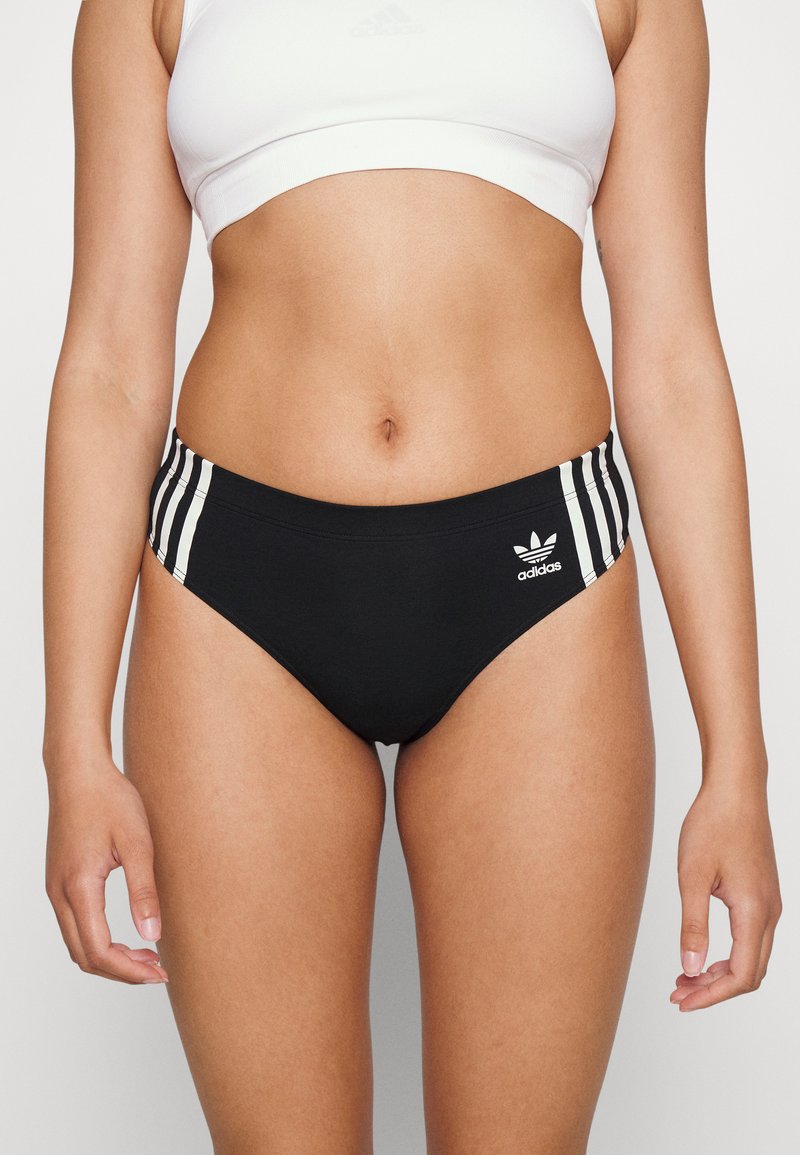 Czarne bikini z niskim stanem z trzema białymi paskami po bokach i białym logo z przodu. Gładki, elastyczny materiał.
