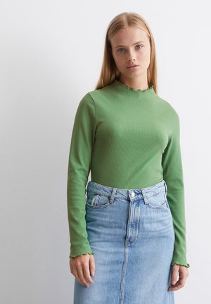 Groene geribbelde longsleeve met een golvende halslijn, gecombineerd met een lichtblauwe denim rok met een hoge taille en recht gesneden.
