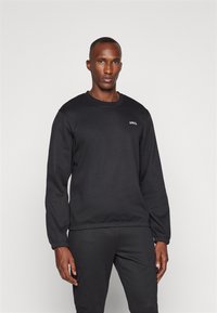 Svart sweatshirt i bomullsblandning, med rund halsringning och ribbade manschetter, samt en liten logotyp på vänster bröst.