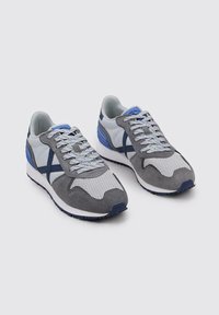 Zapatillas deportivas de ante gris y malla con acentos en marino y azul claro, que cuentan con una suela texturizada y cordones con patrón.