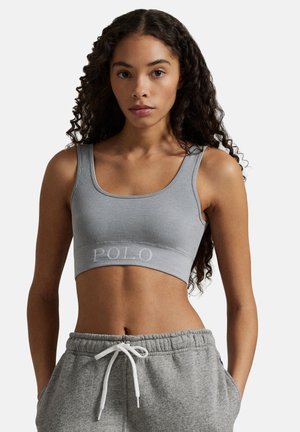 Graues, geripptes Croptop mit rundem Ausschnitt und aufgesticktem "POLO"-Logo auf dem Bund. Kombiniert mit grauen Jogginghosen mit Kordelzug.