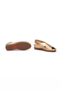 Sandales compensées dorées avec un design perforé, ouverture à l'avant et bride arrière ajustable. Semelle texturée pour adhérence et confort.