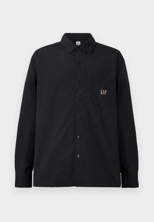 Black long-sleeve button-up shirt with collar and chest pocket featuring a small "GAP" logo patch.