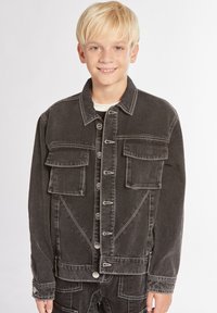 Giubbotto in denim nero con due tasche sul petto, bottoni metallici e dettagli di cucitura bianca. Presenta una vestibilità dritta e maniche lunghe.