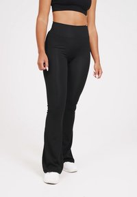 Schwarze Sportleggings mit hohem Bund, aus glattem, elastischem Stoff, mit ausgestelltem Bein Design und minimalen Nähten.