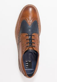 Chaussure en cuir marron avec un avant de chaussure perforé en bleu foncé, design wingtip et détails en brogue complexes. Lacets noirs et intérieur bleu.
