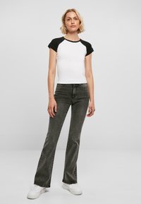 Svart og hvit raglan t-skjorte med korte ermer, kombinert med høy midje og utslåtte mørkegrå jeans og hvite joggesko.