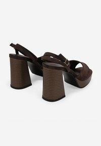 Sandalias de tacón alto de ante marrón con un diseño de punta descubierta, que cuentan con un ancho tacón bloque a rayas y una correa ajustable en la parte trasera.