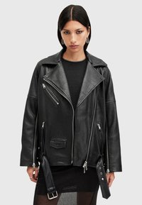 Μαύρο δερμάτινο μπουφάν μοτοσικλέτας με υφή, φαρδύ γιακά, πολλές τσέπες με φερμουάρ και ρυθμιζόμενη λεπτομέρεια λουριού.