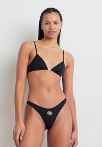 Set de bikini negru, cu un top triunghiular cu bretele subțiri și un slip cu talie joasă, având detalii din metal argintiu în centru.