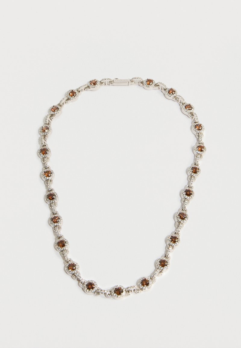 Srebrna ogrlica s krožnimi rjavimi kamni, vstavljenimi v podrobne kovinske povezave, opremljena z varnim zaponkom. Dizajn ima teksturirano površino.
