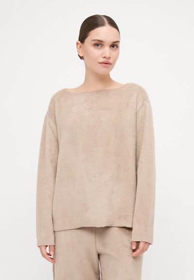 Pull beige, doux, à manches longues avec un col large et une coupe semi-détendue. Présente une surface texturée et se marie avec un bas assorti.