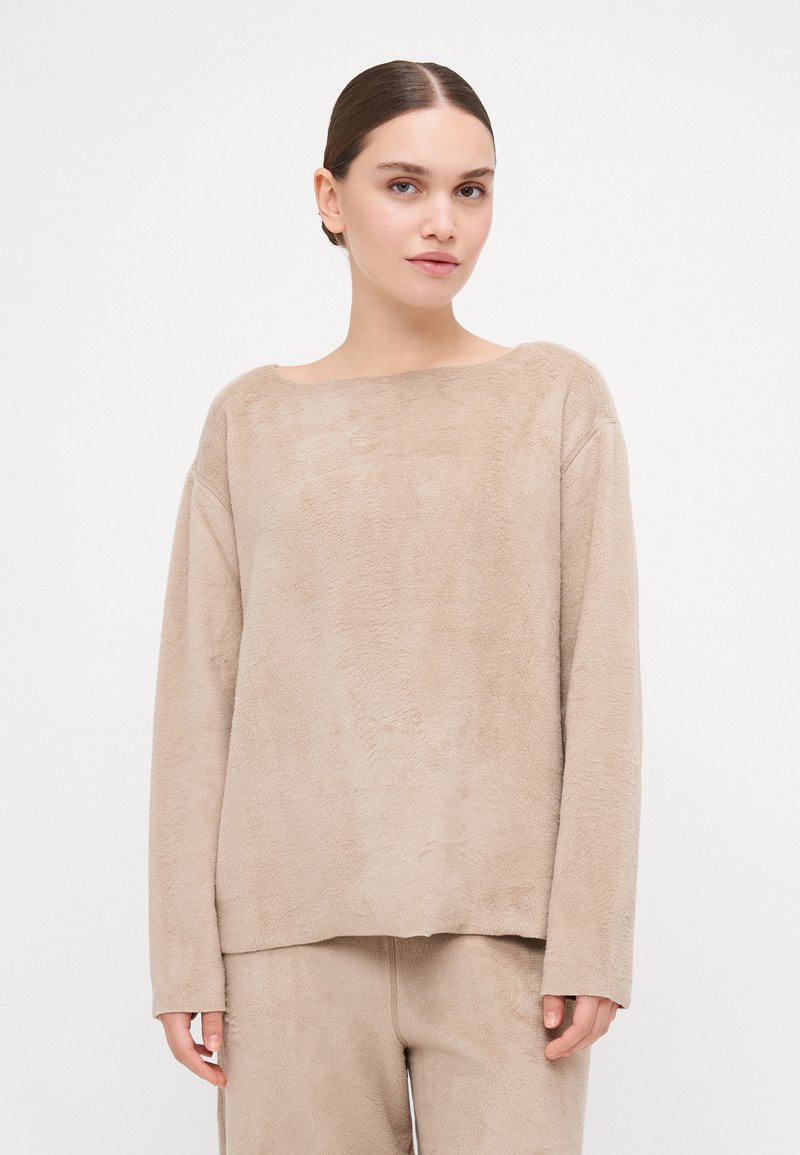 Beige, soft, long-sleeve sweater with a wide neckline and semi-relaxed fit. Features a textured surface and pairs with matching bottoms.