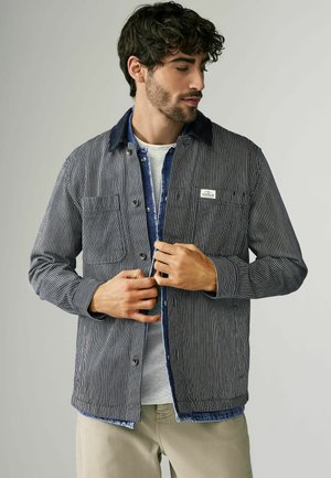 Gestreepte jacket met een knoopsluiting, denim kraag, twee borstzakken en een gestructureerde stof. Draag het over een lichtgrijze shirt.