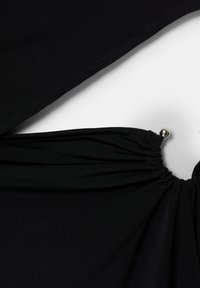 Details des schwarzen Kleidungsstücks zeigen glattes Material mit geraffter Textur. Es hat ein silbernes Akzent am gerafften Bereich, was ein elegantes Erscheinungsbild erzeugt.
