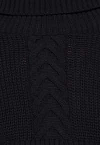 Black knitted sweater featuring a ribbed turtleneck, intricate cable knit pattern at the center, and textured stitch detailing on sides.